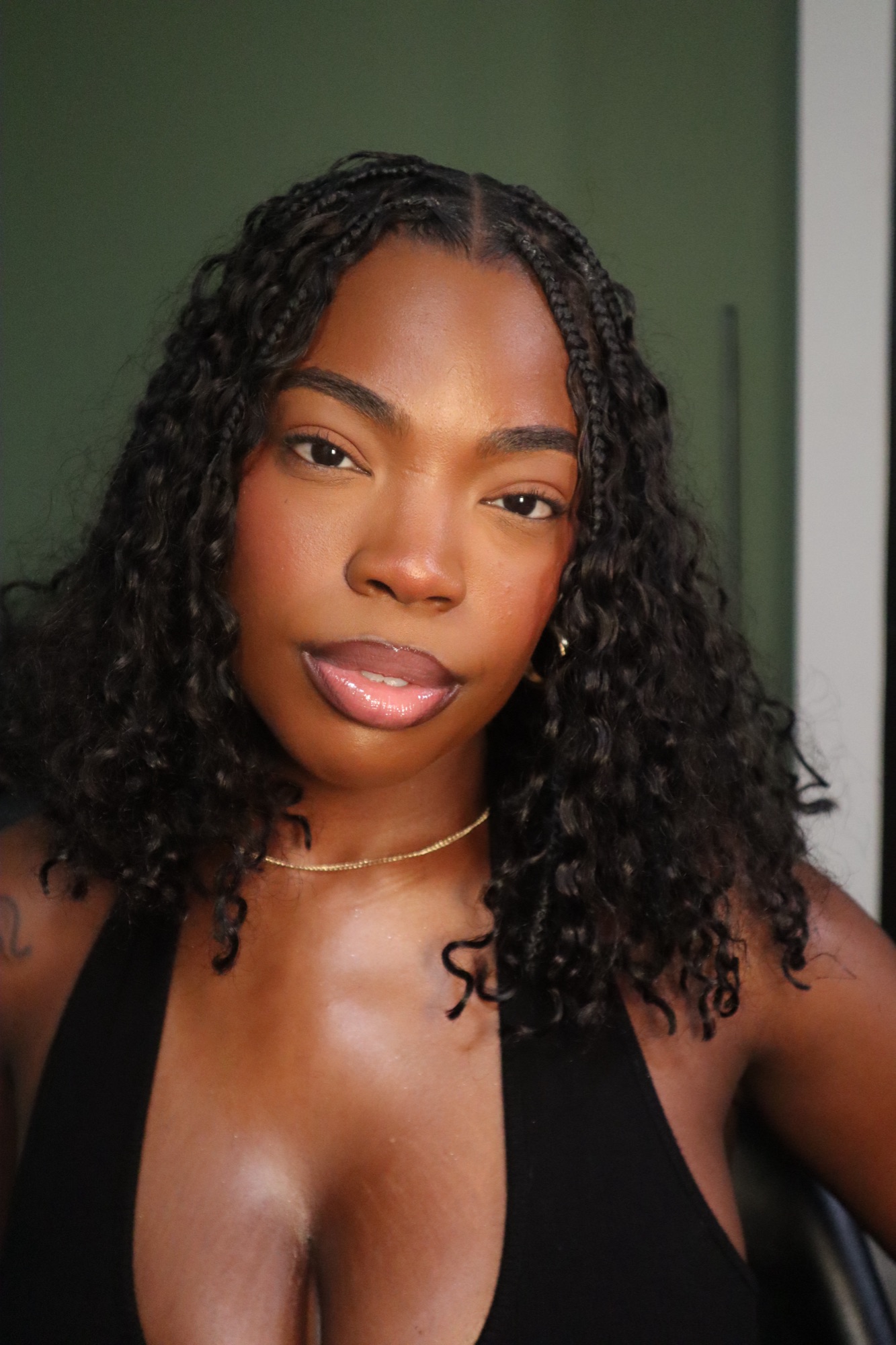 Woman wearing knotless braids styled down with a natural makeup look.