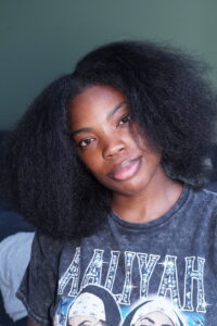 Black girl showing her stretched, blown-out natural hair before creating the twists.